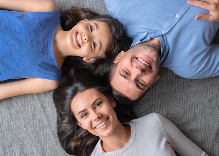 Happy family concept. Top view of happy family of three bonding to each other and smiling while lying on the floor